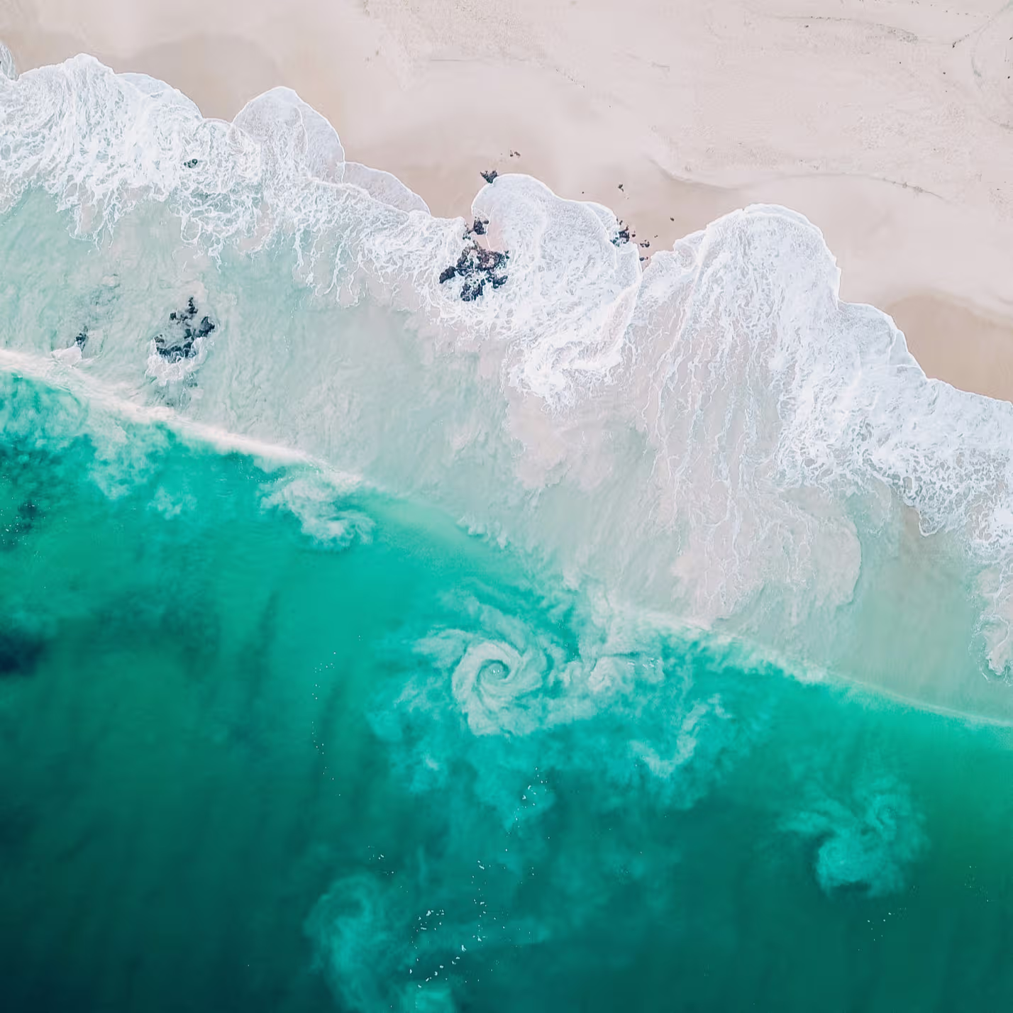 Aerial view of ocean waves meeting a beach shoreline